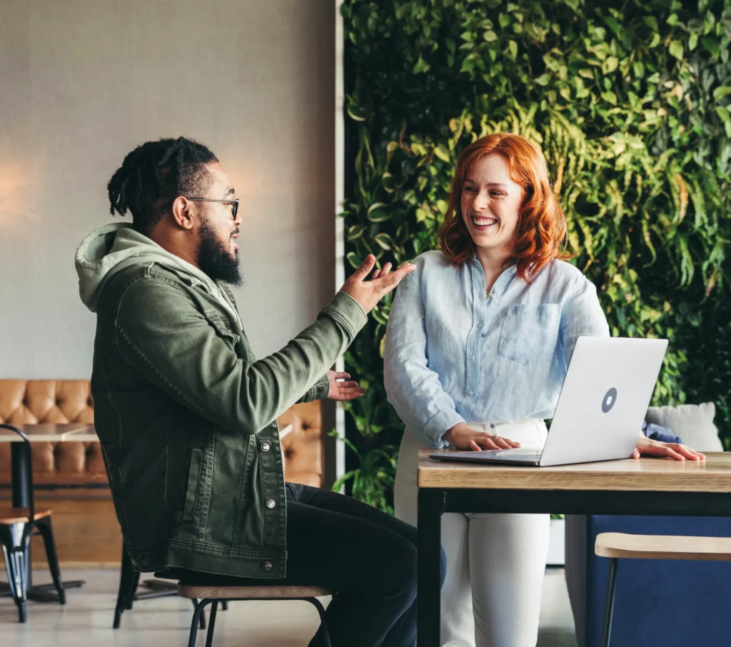 Två personer i samtal vid laptop som symboliserar Prosavios fokus på entreprenörskap, partnerskap och nya affärsmöjligheter.